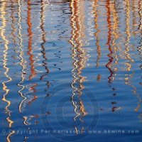 Reflections of sailboat masts in the water in the Barcelona harbour