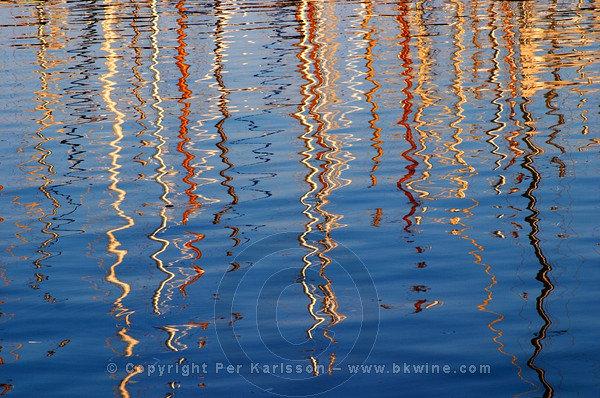 Reflections of sailboat masts in the water in the Barcelona harbour