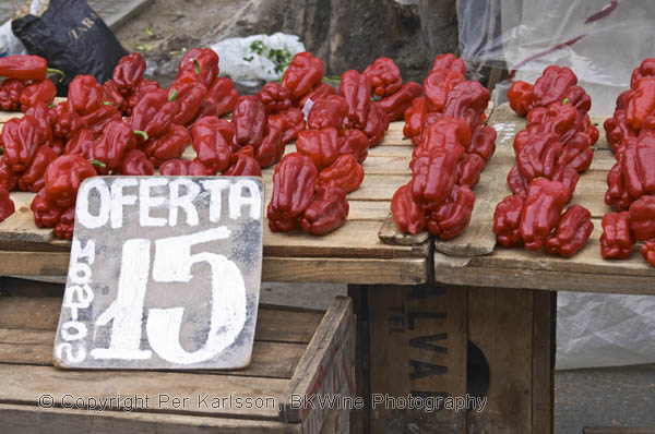 A street market stall selling red bell peppers